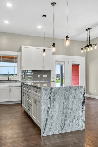 a kitchen with stainless steel appliances granite countertop a stove a sink and white cabinets with wooden floor
