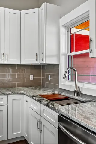 a kitchen with granite countertop a sink and white cabinets