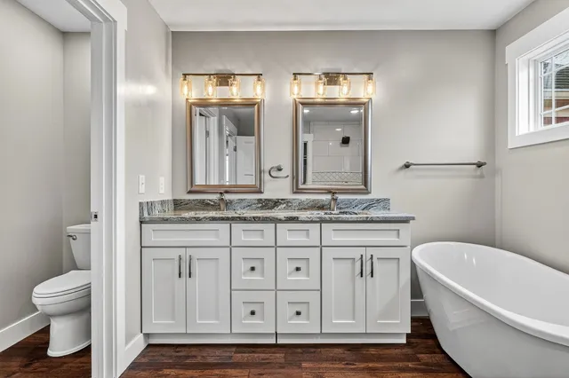 a bathroom with a granite countertop sink a toilet and a bathtub