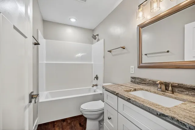 a bathroom with a granite countertop toilet sink and mirror
