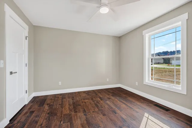 a view of an empty room with wooden floor and a window