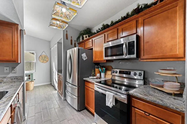 a kitchen with stainless steel appliances granite countertop a stove microwave refrigerator and sink