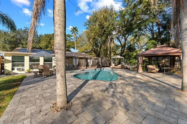 a view of a patio with table and chairs under an umbrella with large trees