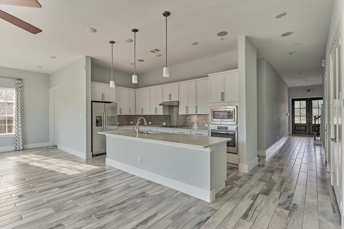 2113 Solstice Boulevard Spring, TX 77386 - Photo 23 of 50 a large kitchen with kitchen island a stove a sink dishwasher a refrigerator and white cabinets with wooden floor