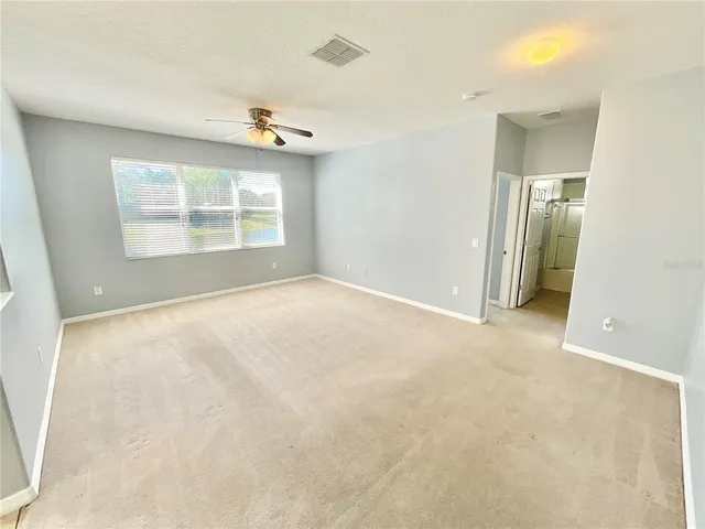 an empty room with windows and a ceiling fan