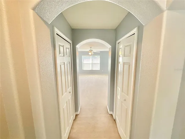 an empty room with windows and chandelier fan