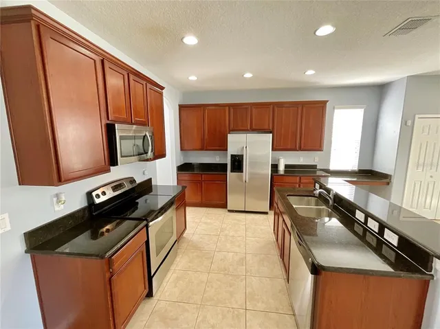 a kitchen with stainless steel appliances granite countertop a stove a sink and a microwave