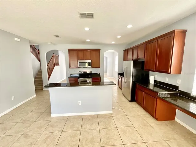a large kitchen with stainless steel appliances granite countertop a refrigerator and a stove top oven