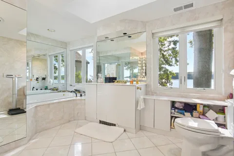 a large white bathroom with a tub a sink and a large mirror