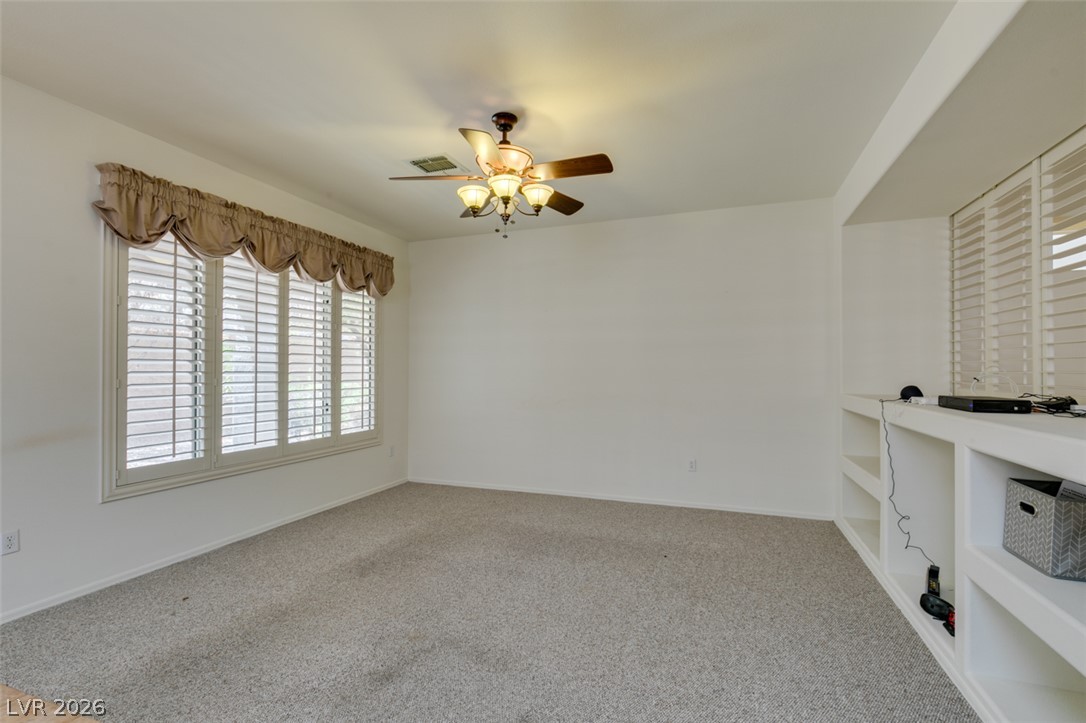2189 Chapman Ranch Drive Henderson, NV 89012 - Photo 17 of 60 Plentiful natural light fills a versatile living space featuring integrated media shelving and carpeting.