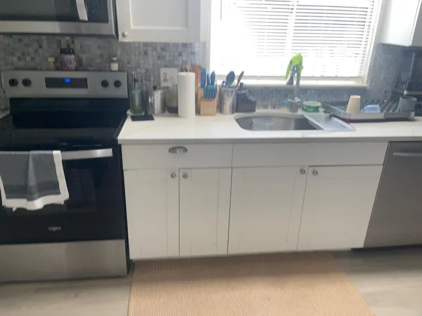 a kitchen with granite countertop white cabinets and a sink