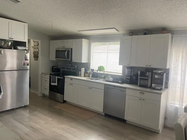 a kitchen with granite countertop a refrigerator stove top oven and sink