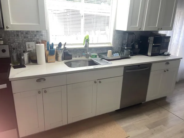 a kitchen with stainless steel appliances white cabinets a sink and a window