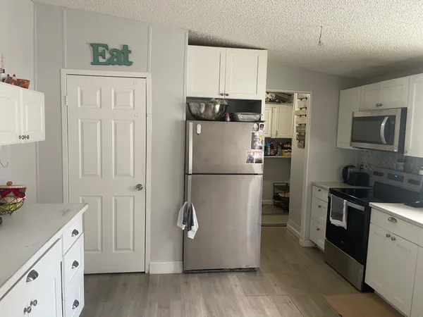 a kitchen with cabinets stainless steel appliances and wooden floor