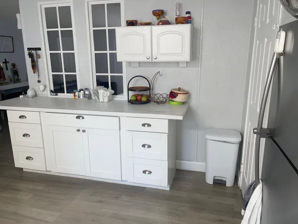 a white kitchen with a sink a toilet and a refrigerator