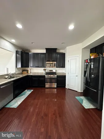 a kitchen with stainless steel appliances granite countertop a refrigerator a sink dishwasher a stove and a oven with wooden floor