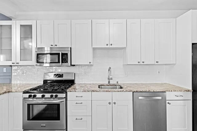 a kitchen with stainless steel appliances granite countertop white cabinets a stove a sink and dishwasher