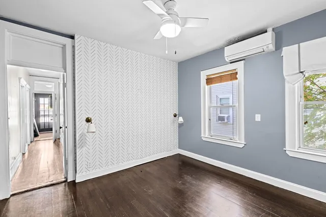 an empty room with wooden floor fan and windows