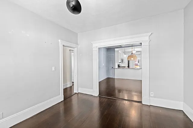 an empty room with wooden floor cabinet and windows