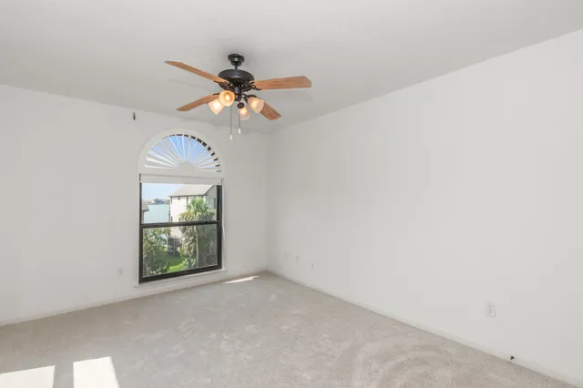 an empty room with windows and fan