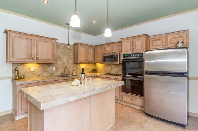 a kitchen with stainless steel appliances granite countertop a sink refrigerator and cabinets