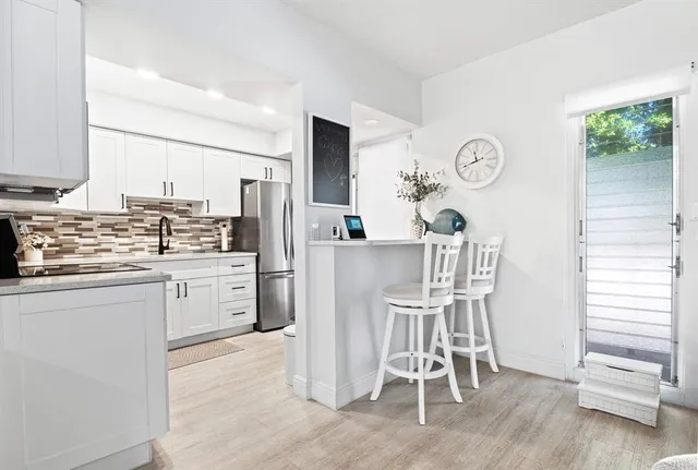 a kitchen with stainless steel appliances kitchen island granite countertop a table chairs cabinets and wooden floor