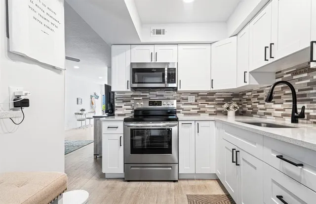 a kitchen with cabinets stainless steel appliances and sink