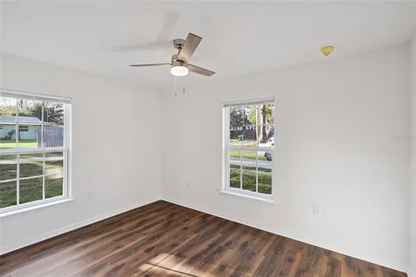 a view of an empty room with a window and wooden floor