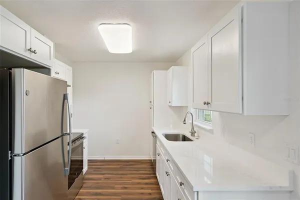 a kitchen with stainless steel appliances a refrigerator a sink and white cabinets