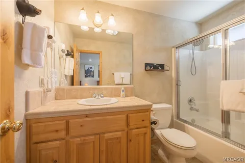 a bathroom with a sink a toilet a mirror a vanity and shower