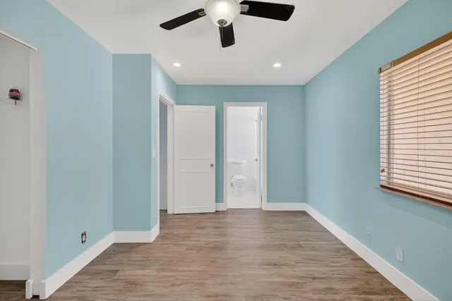 a view of an empty room with window and wooden floor