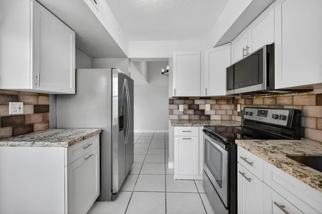 a kitchen with stainless steel appliances granite countertop a stove a sink and a microwave