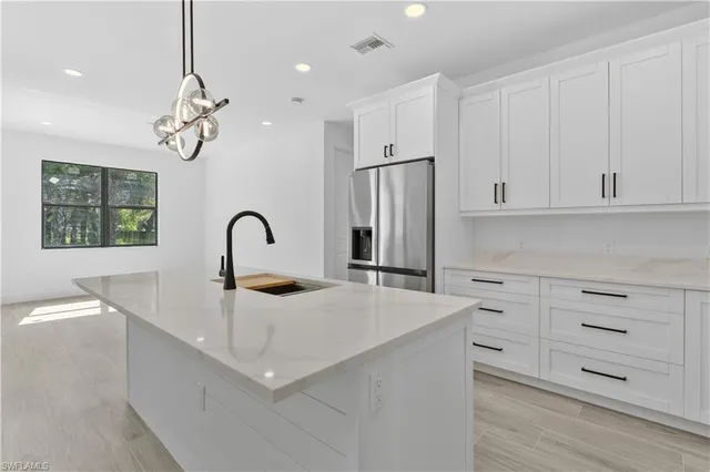 a kitchen with stainless steel appliances granite countertop a sink a stove a refrigerator and white cabinets with wooden floor