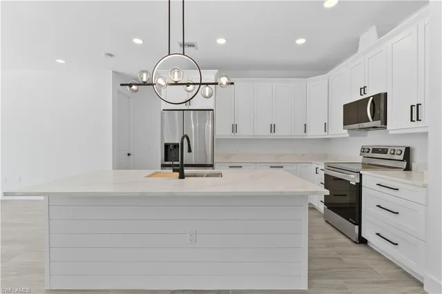a view of kitchen with kitchen island white cabinets and refrigerator