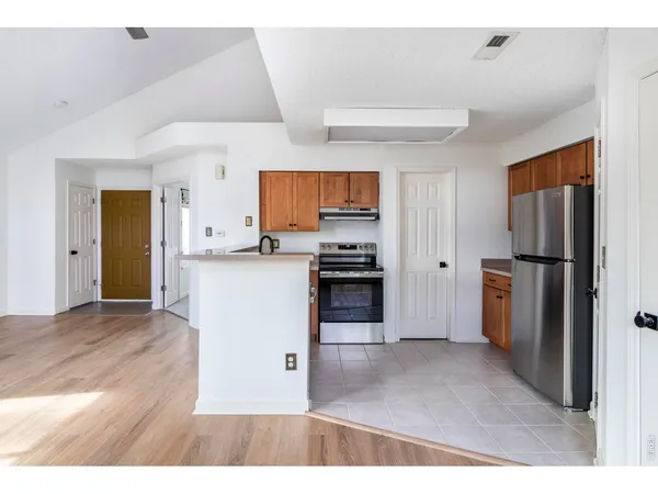 a kitchen with a refrigerator and a wooden cabinets