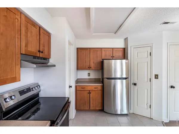 a kitchen with a refrigerator a stove top oven a sink dishwasher and wooden cabinets