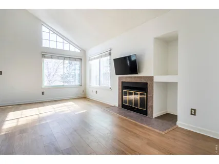 a view of empty room with wooden floor and fireplace
