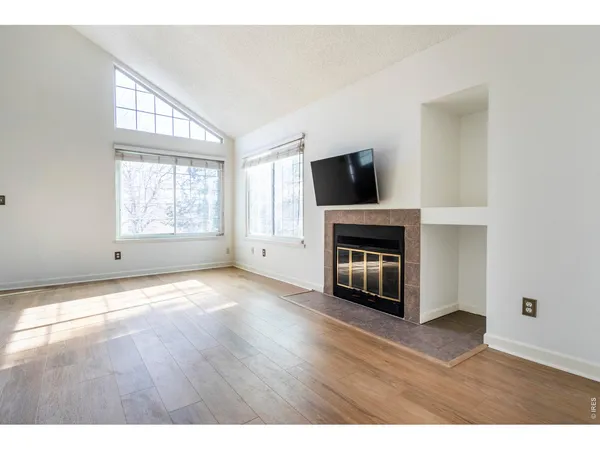 a view of empty room with wooden floor and fireplace