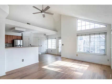 a view of an empty room with a window and a kitchen area