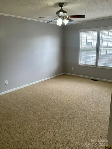 an empty room with windows and ceiling fan