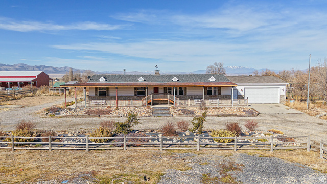 Ranch-style residence featuring a covered front porch, an attached garage, and stone accent siding