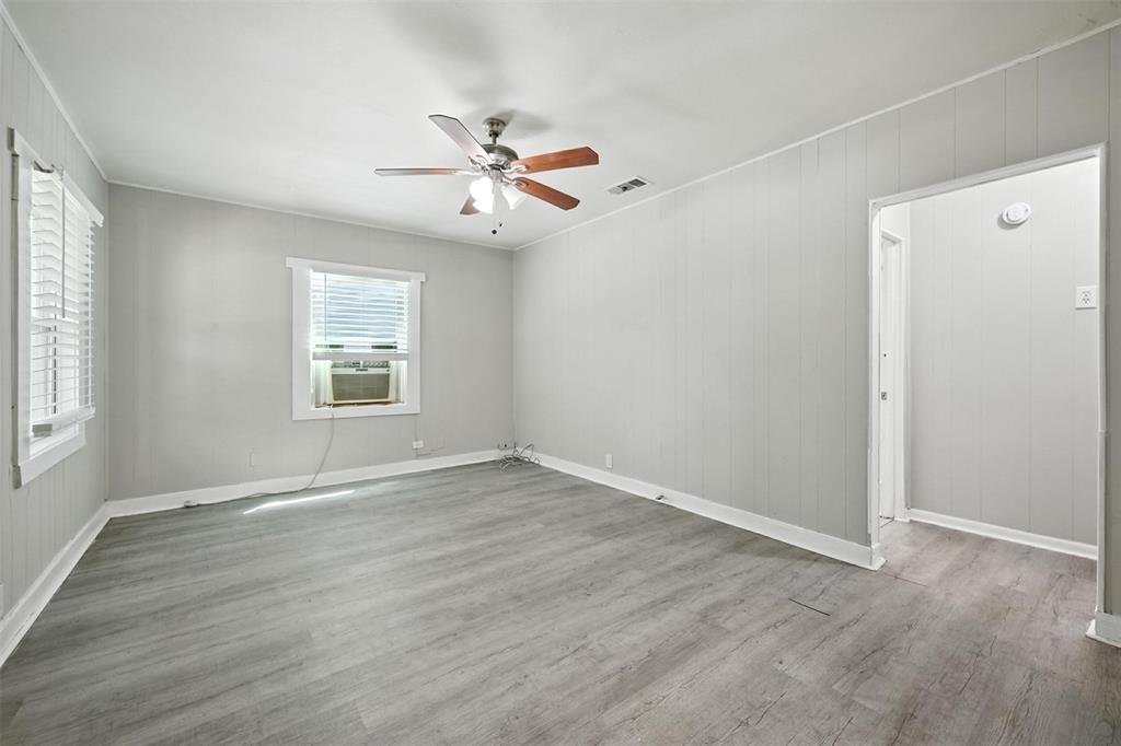 204 Graham Avenue Bonham, TX 75418 - Photo 8 of 21 Empty room with light wood finished floors, wood walls, a ceiling fan, and ornamental molding