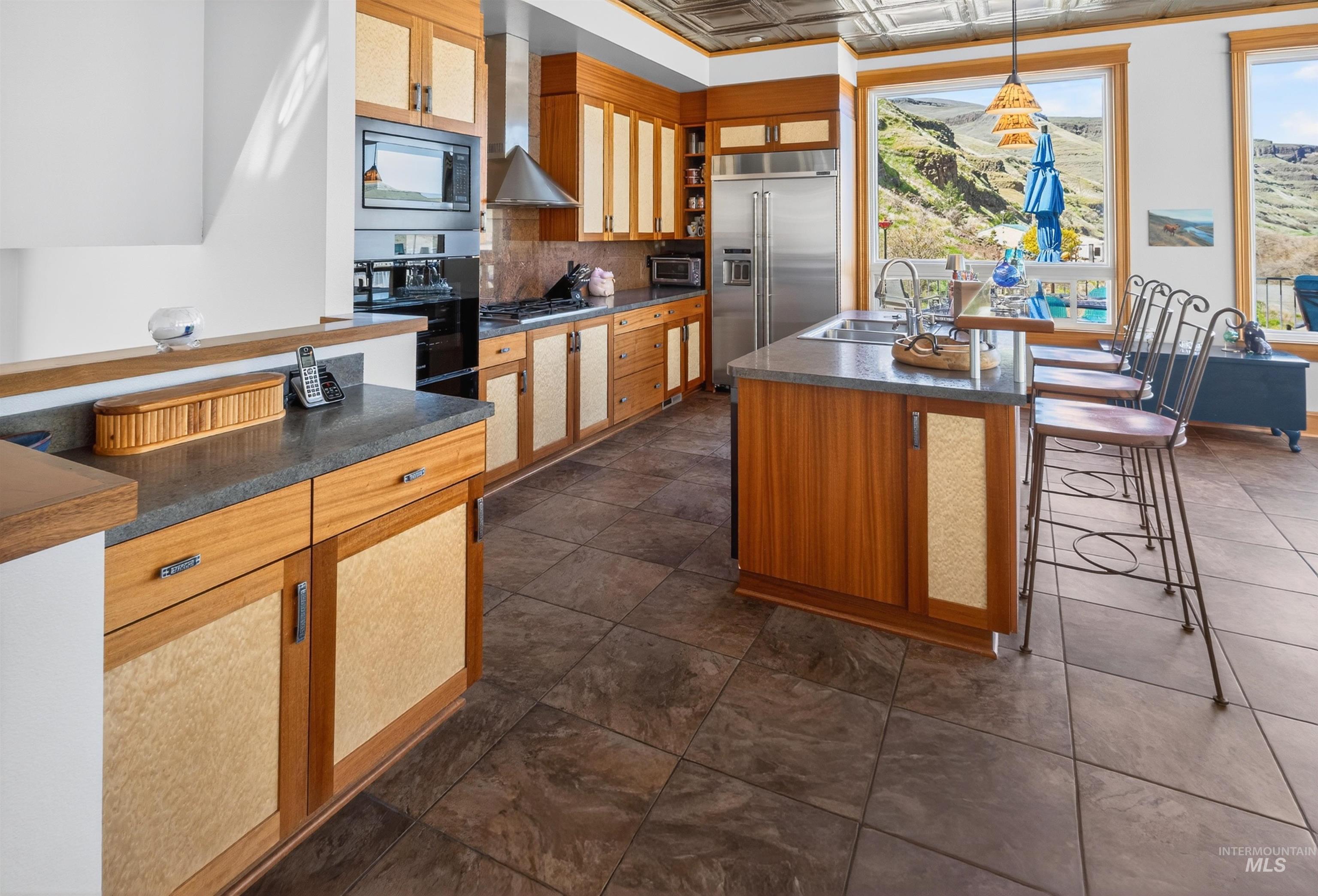 6382 Snake River Road Asotin, WA 99402 - Photo 13 of 34 Kitchen with wood finish cabinetry, an ornate ceiling, dark countertops, a kitchen bar, and a center island with sink