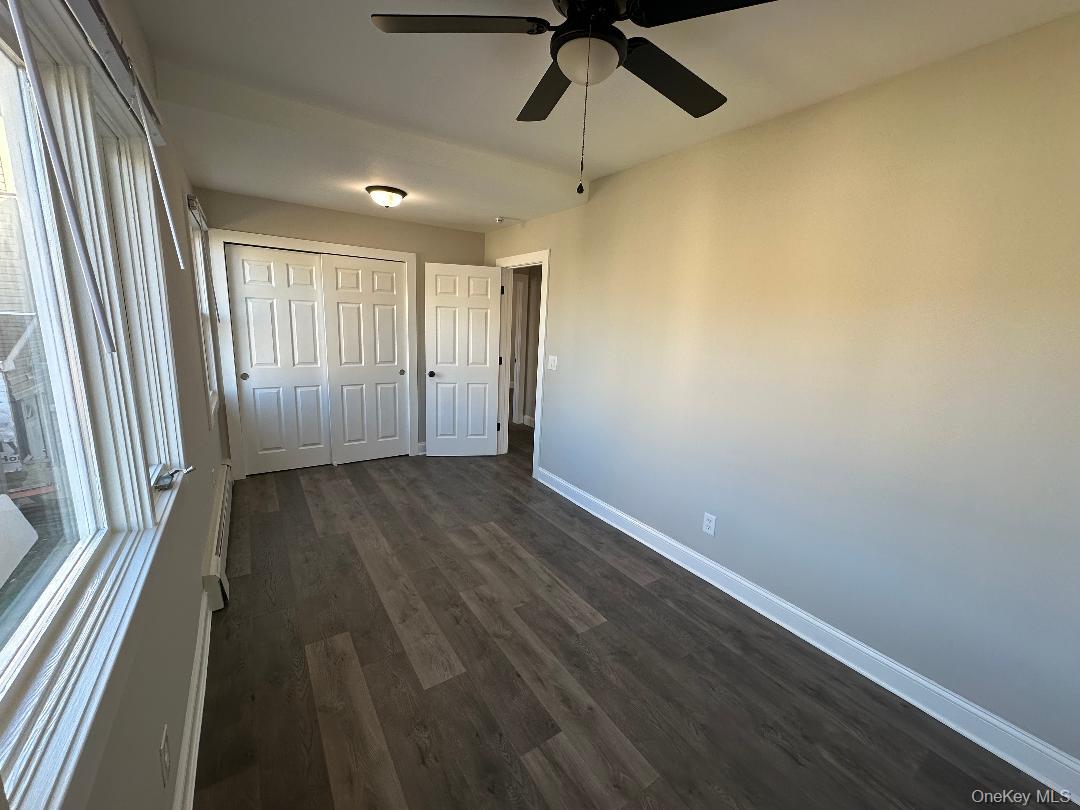 84 Rochester Avenue, Unit MAIN Long Beach, NY 11561 - Photo 20 of 27 en empty room with wooden floor fan and windows