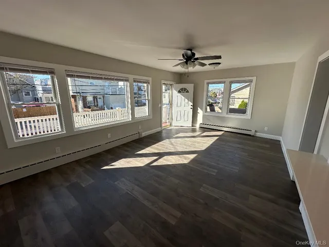 a view of an empty room with a window and a kitchen