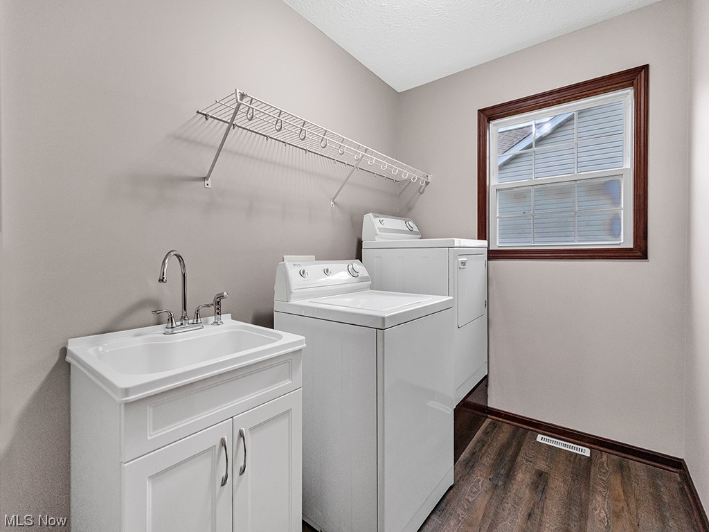 891 Susan Road Ravenna, OH 44266 - Photo 22 of 28 Washroom featuring sink, dark hardwood / wood-style floors, cabinets, and washer and clothes dryer