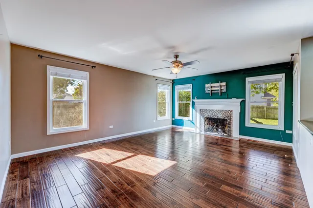 an empty room with windows a fireplace and wooden floor