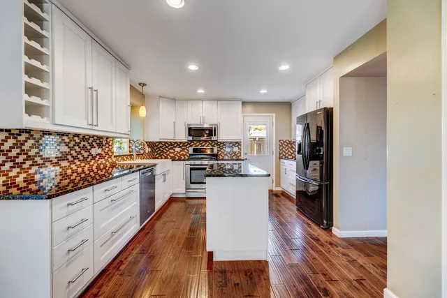 a kitchen with granite countertop a refrigerator stove top oven and sink