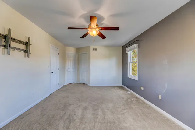 an empty room with windows and fan