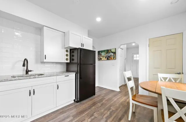 a kitchen with a refrigerator a sink dishwasher a dining table and chairs with wooden floor